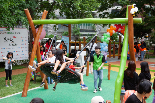 코오롱그룹은 2016년부터 사회복지공동모금회 지정기탁사업으로 세이브더칠드런과 도시 놀이터 개선사업에 참여하고 있다.  2019년 강서구 다운어린이공원 개장식에서 아이들에게 바구니그네를 밀어주고 있는 코오롱사회봉사단. <코오롱그룹 제공>